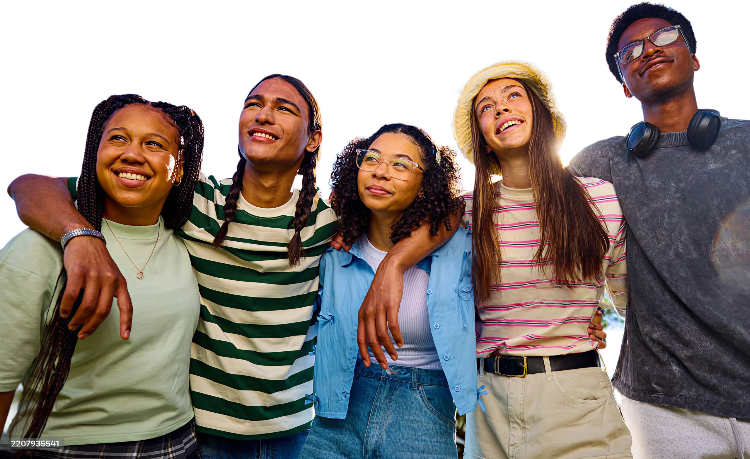 Cinq jeunes adultes souriants se tiennent serrés les uns contre les autres en plein air, les bras autour des épaules, le regard tourné vers le ciel. Ils ont l'air détendus et heureux, vêtus de tenues décontractées, avec un ciel clair et ensoleillé en arrière-plan.