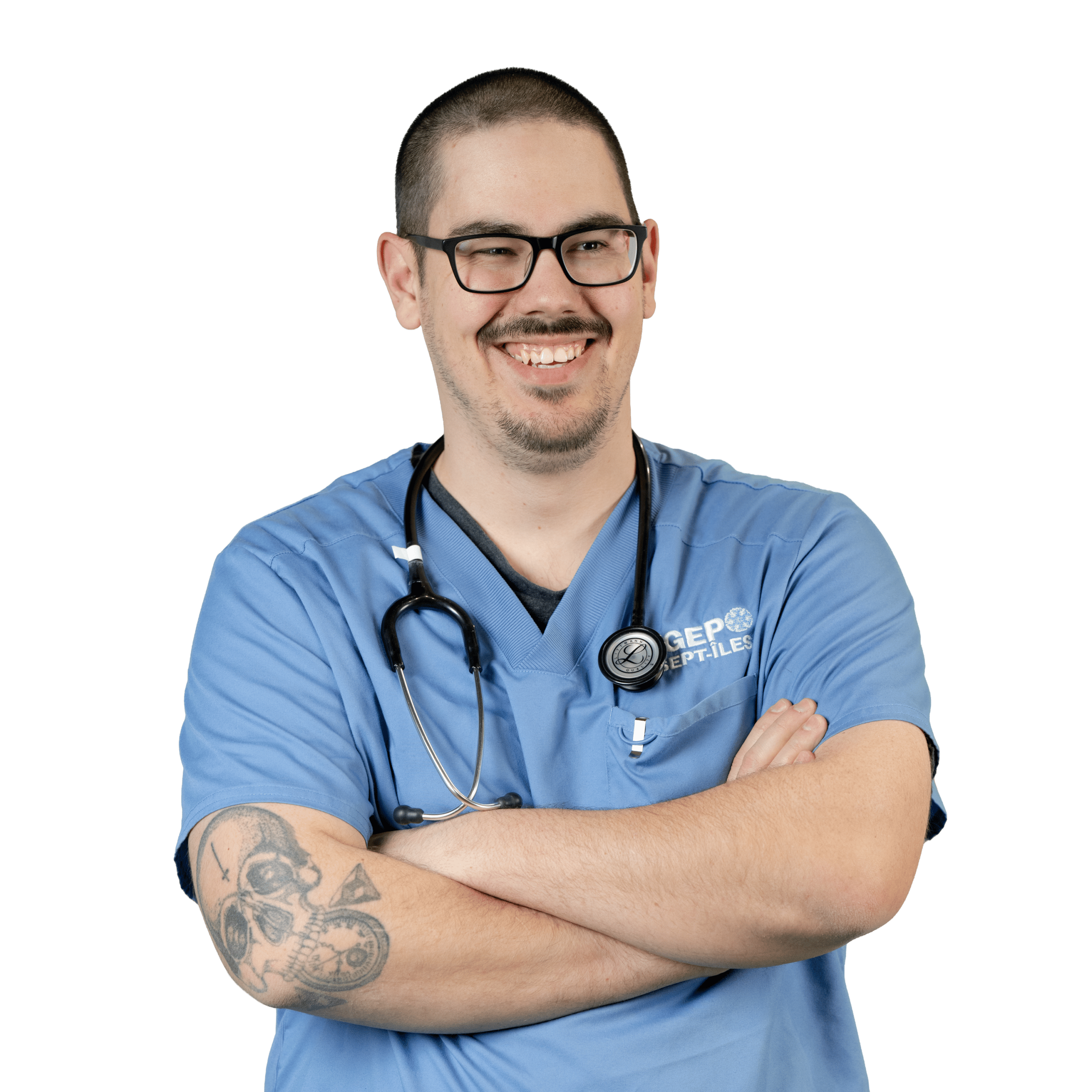 Un professionnel de santé souriant, vêtu d'une blouse bleue et portant un stéthoscope autour du cou, se tient debout, les bras croisés, dévoilant un tatouage sur son avant-bras.