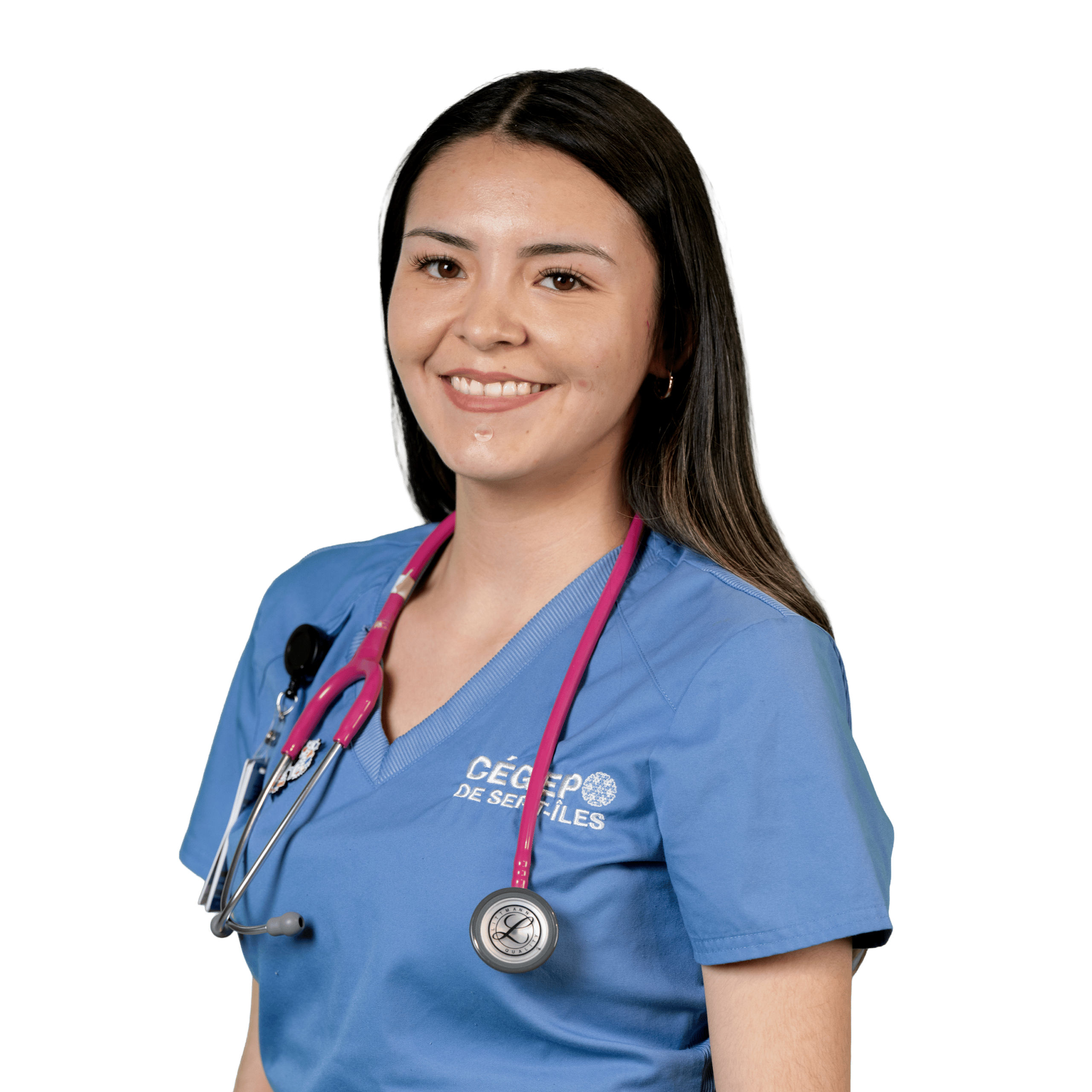 Une femme vêtue d'une blouse médicale bleue et portant un stéthoscope rose sourit à la caméra devant un fond blanc uni.