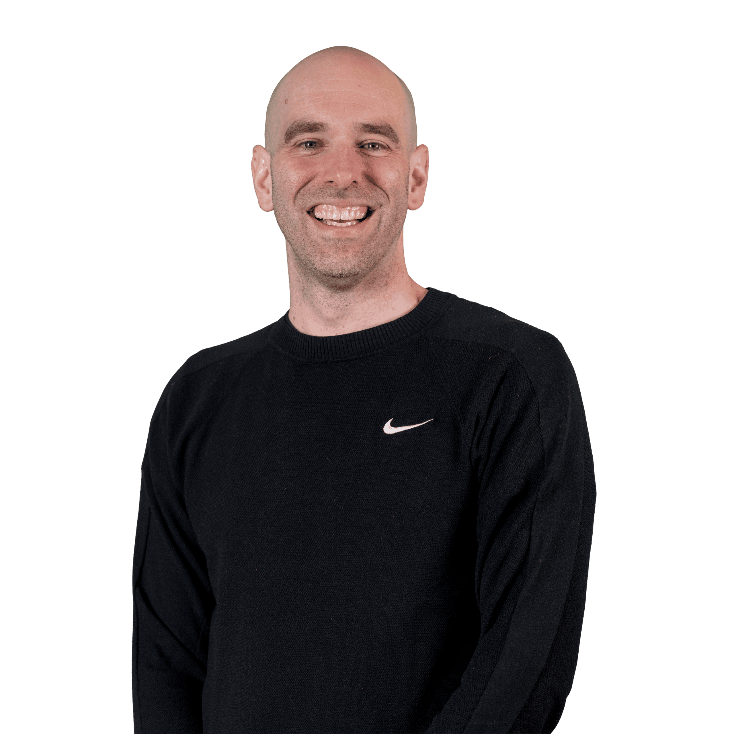 Une personne souriante, au crâne rasé, vêtue d'un pull Nike noir, debout devant un fond blanc uni.