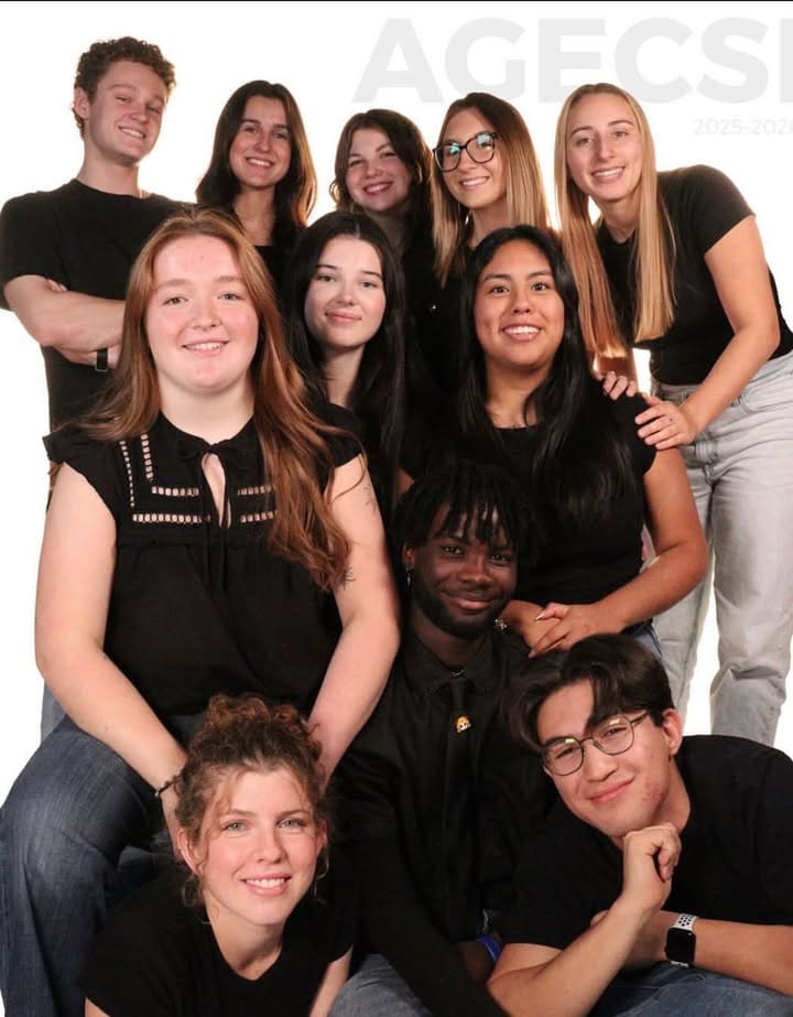 Douze jeunes adultes souriants posent ensemble sur un fond blanc ; certains sont assis et d’autres debout derrière eux, tous vêtus d’un haut noir et d’un jean. Le groupe semble heureux et très soudé.